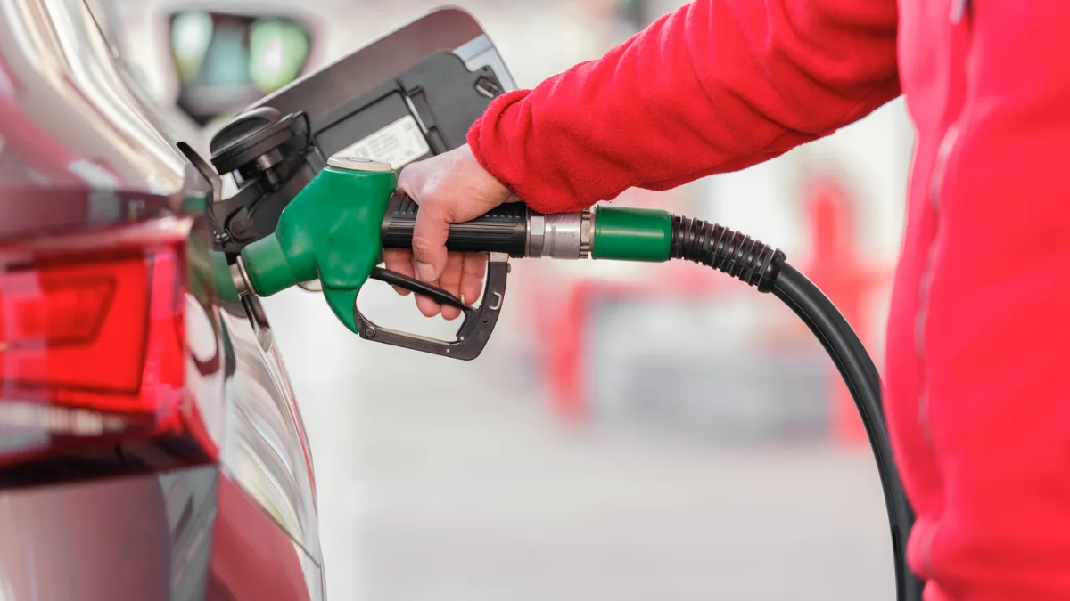 faire-le-plein-essence-pistolet-vert-e85 Main remplissant un réservoir avec un pistolet d'essence vert