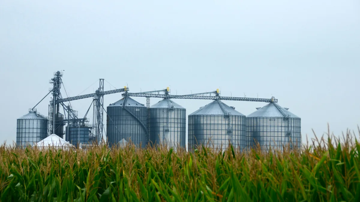 silos-stockage-mais-bioethanol-e85 Silos de stockage devant un champ de maïs, matière première du bioéthanol E85